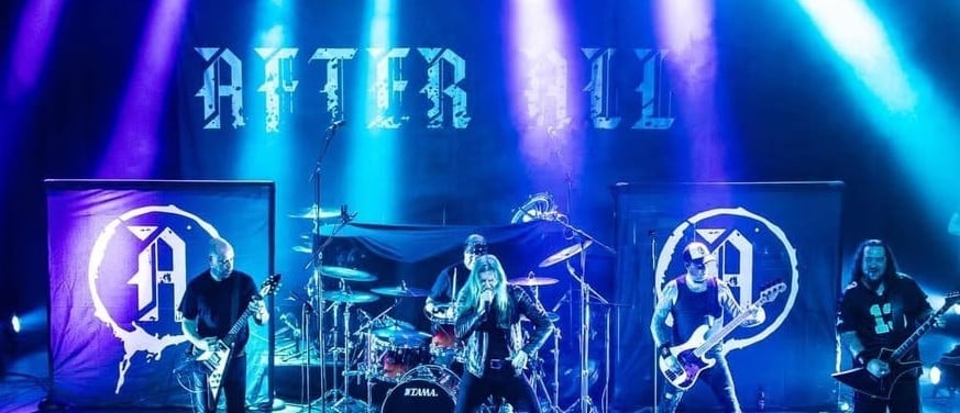 Live band performing on stage with blue and purple stage lighting and neon band logo displays